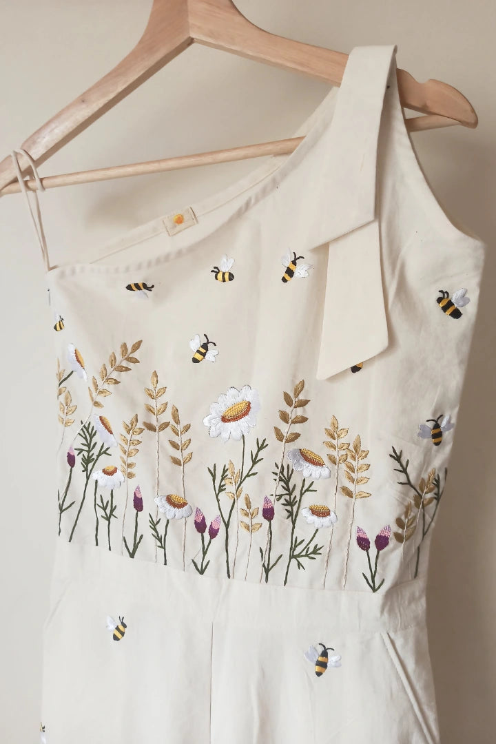 Ilamra sustainable clothing organic cotton Off-white hand block printed jumpsuit which comes with slightly flared pants with side hip slant pockets, side zip closure and hand-embroidered lush flower beds and honey bees. Cool and convenient to wear
